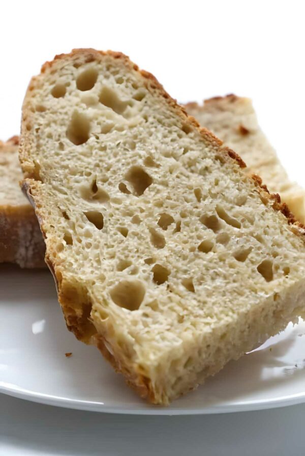 Two slices of rustic artisan bread on a white plate, close-up.