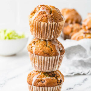 A stack of sourdough zucchini muffins with glaze dripping down them.