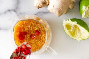 Whisking a chili, lime, and ginger dressing in a bowl.
