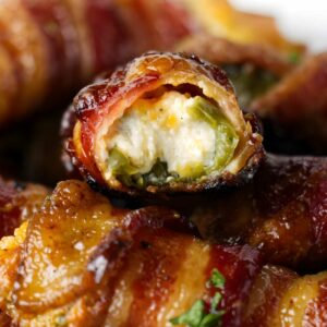 Close-up of bacon-wrapped jalape&ntilde;o poppers with creamy cheese filling.
