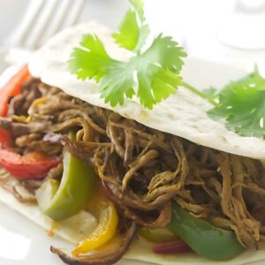 Close-up of shredded beef fajitas made with tri tip, bell peppers, and cilantro.