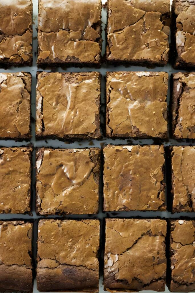 Neatly arranged rows of glossy, crackle topped brownies.