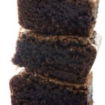 Stack of three rich, fudgy chocolate brownies with shiny texture.