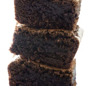 Stack of three rich, fudgy chocolate brownies with moist texture.