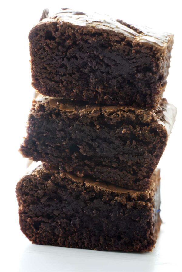Stack of three rich, fudgy chocolate brownies with shiny texture.