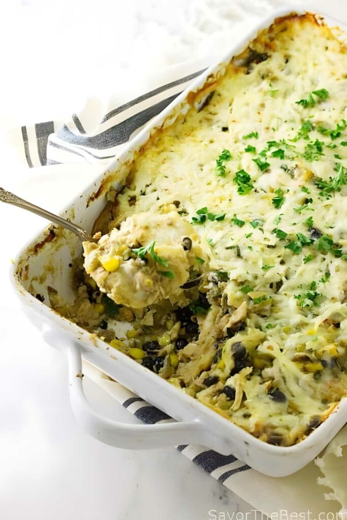 Creamy chicken shepherds pie with cheese topping; spoon reveals filling.