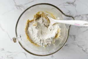 Adding flour to chocolate chip cookie dough to make levain bakery cookies.