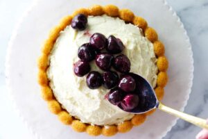 Topping a cake with cherry compote.