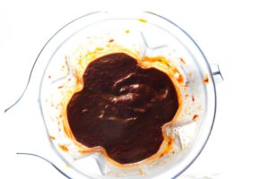 Blending red chile sauce in a blender.