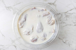 Several chicken pieces getting brined in buttermilk.