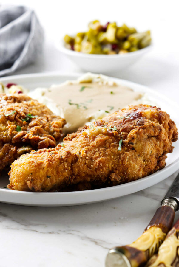Two pieces of buttermilk fried chicken on a plate with mashed potatoes.