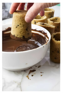 A hand showing how to make cookie shot glasses with chocolate coating.