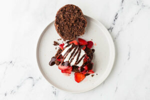 Laying a sourdough shortcake with strawberries and whipped cream.