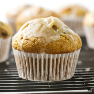 A zucchini muffin on a cooling rack with a sweet glaze.