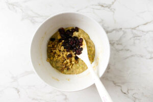 Adding toasted nuts and raisins to zucchini muffin batter recipe.