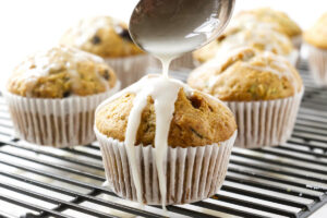 Drizzling a vanilla glaze on top of homemade zucchini muffins.