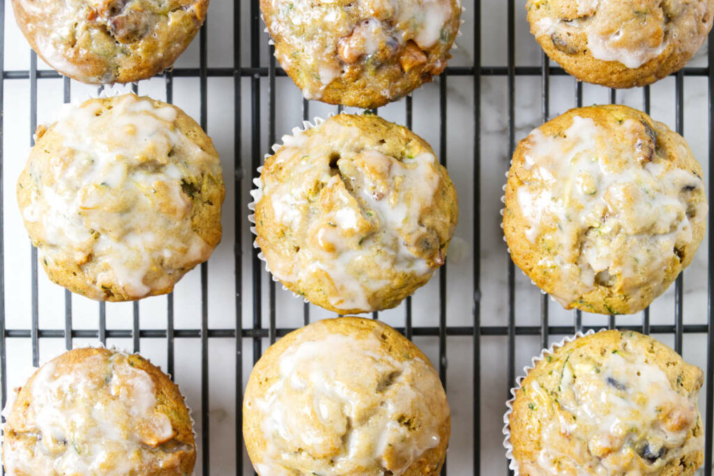 Several muffins on a cooling rack topped with a sweet vanilla glaze.