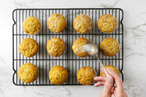 Adding glaze to the top of mango muffins.