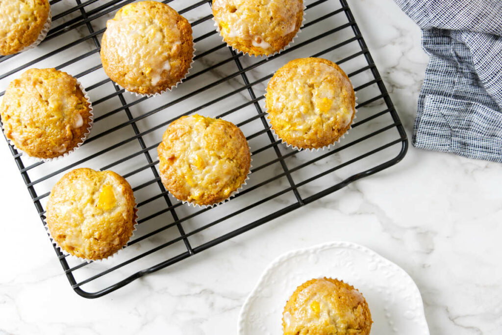 Several coconut mango muffins on a cooling rack.