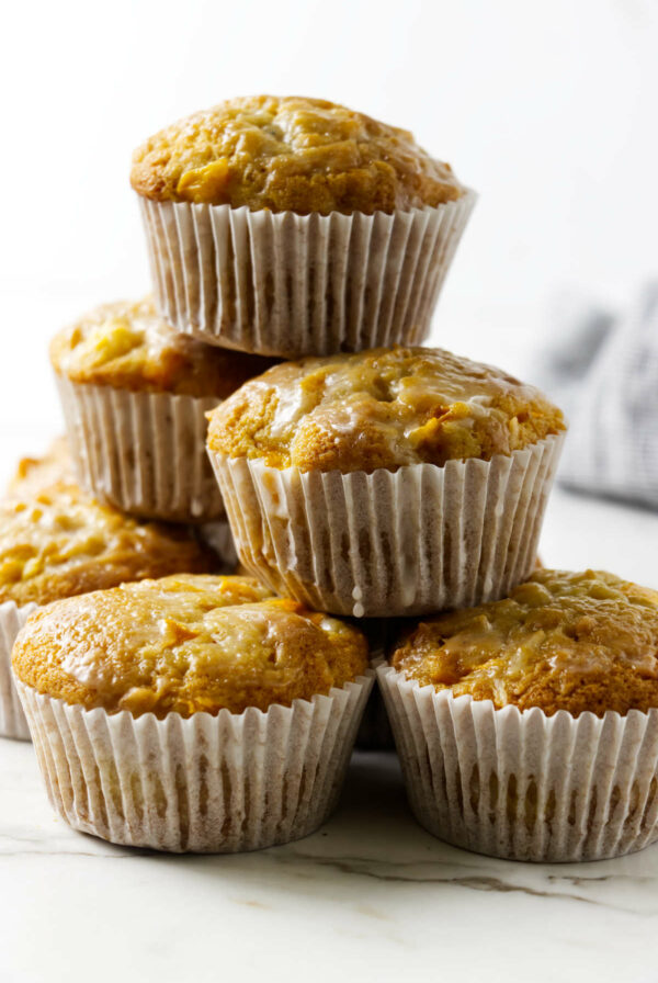 A stack of coconut mango muffins topped with glaze.