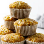 A stack of six coconut mango muffins wrapped in paper.