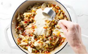 Adding white sauce to crab enchilada filling.