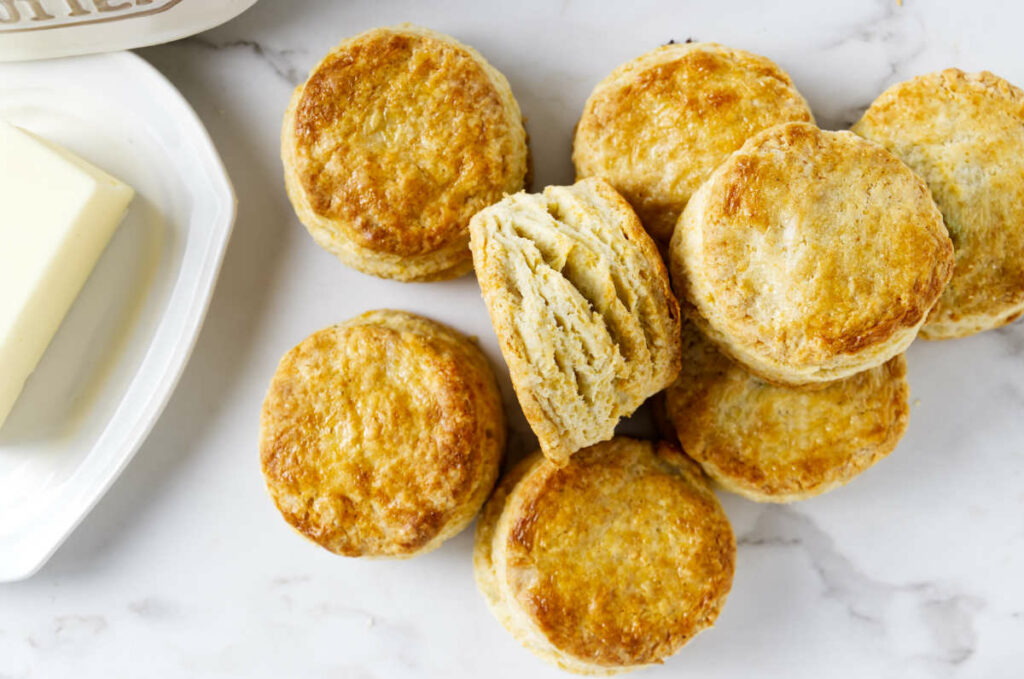 Golden brown breakfast biscuits next to a cube of butter.