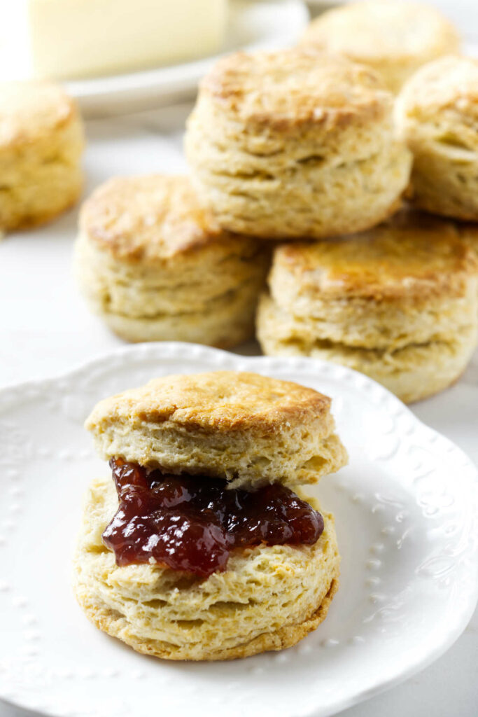 Strawberry jam on a biscuit with five more sourdough biscuits in the background.