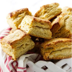 A stack of homemade flaky biscuits in a white bowl.