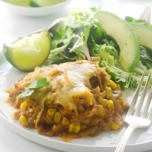 A serving of polenta chicken enchilada on a plate with avocado slices.