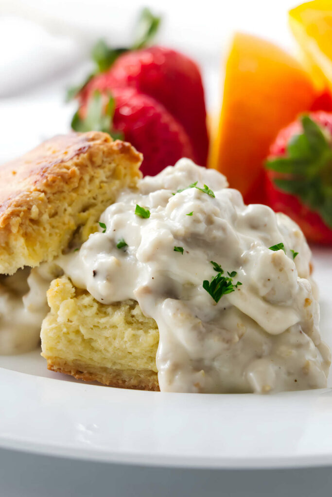 Sausage gravy on a biscuit with parsley on top.