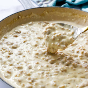 A spoon scooping some sausage gravy from a skillet.