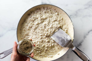 Adding pepper to stovetop sausage gravy.