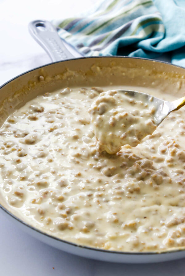 Sausage breakfast gravy in a skillet with a spoon.