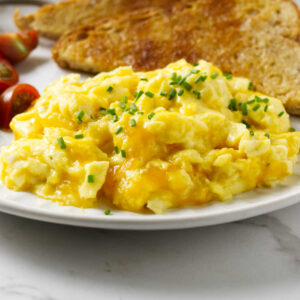 Scrambled egg with cheese on a plate with toast.