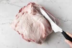 Slicing the fat cap off a pork butt.