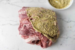 Slathering mustard over a boneless pork butt.