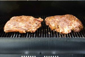 Two Boston pork butts on a pellet grill.