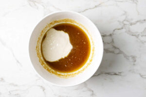 Adding sourdough starter to a bowl with wet ingredients.