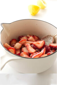 Sliced strawberries in a saucepan with sugar.