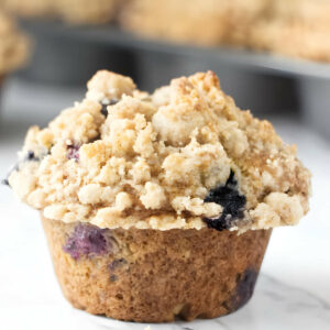 A freshly baked muffin with a streusel topping and blueberries.