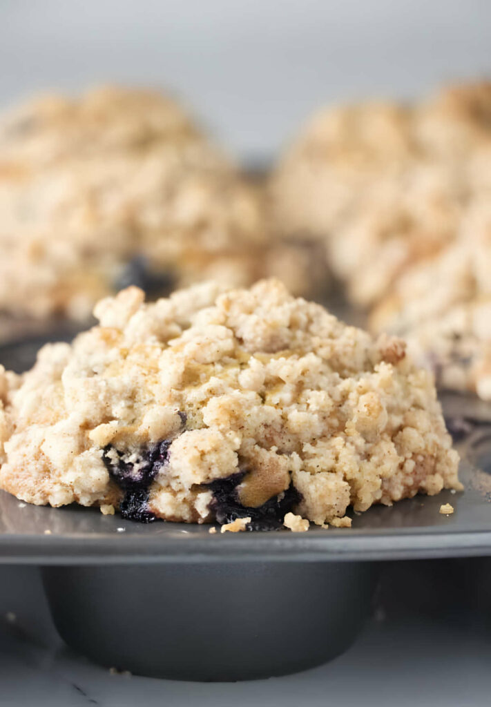 A domed muffin top on top of a gray muffin tin.
