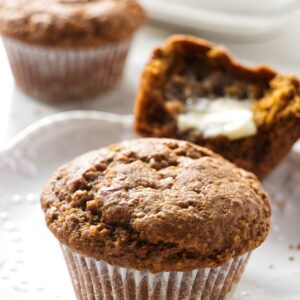 Close-up of a moist bran muffin on white plate, others in background.