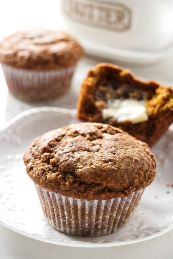 Close-up of a moist bran muffin on white plate, others in background.