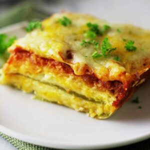 Close-up of cheesy green chile casserole slice garnished with parsley.