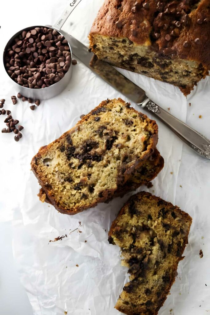 Overhead view of sliced chocolate chip banana bread with scattered chocolate chips.
