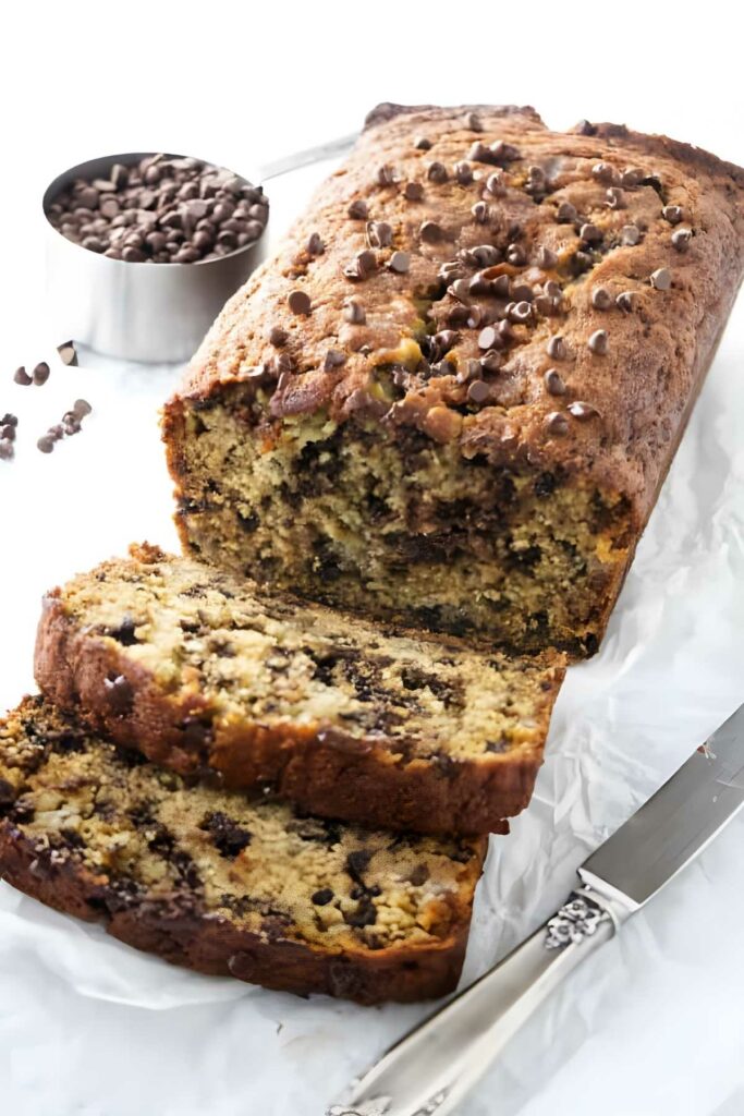 Chocolate chip banana bread with two slices cut, on parchment paper.