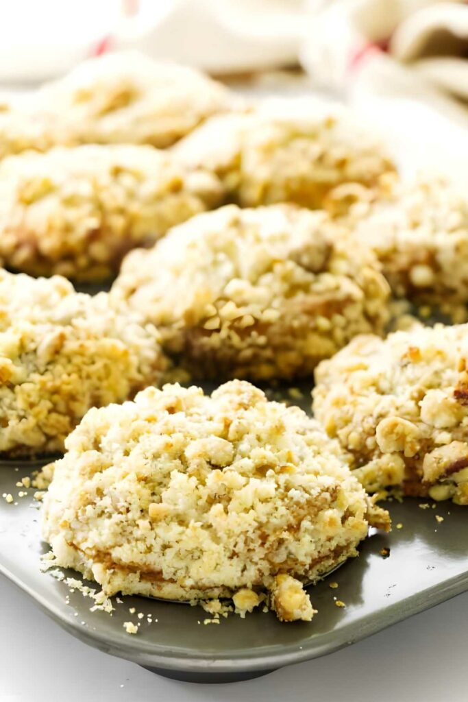 Close-up of cranberry muffins with streusel topping on a baking tray.