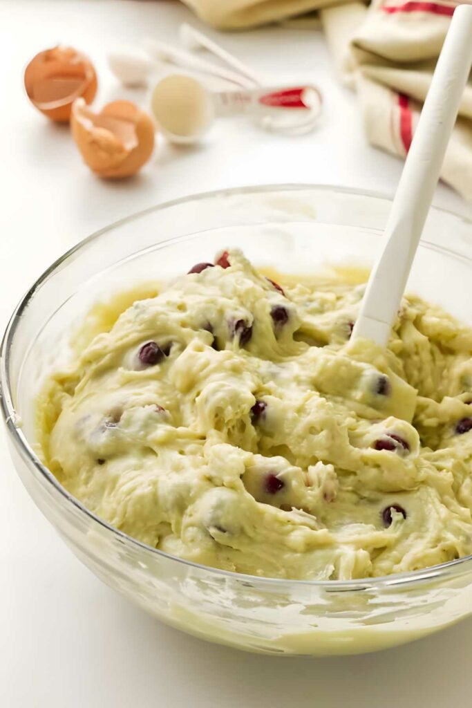 Glass bowl with muffin dough and spatula.