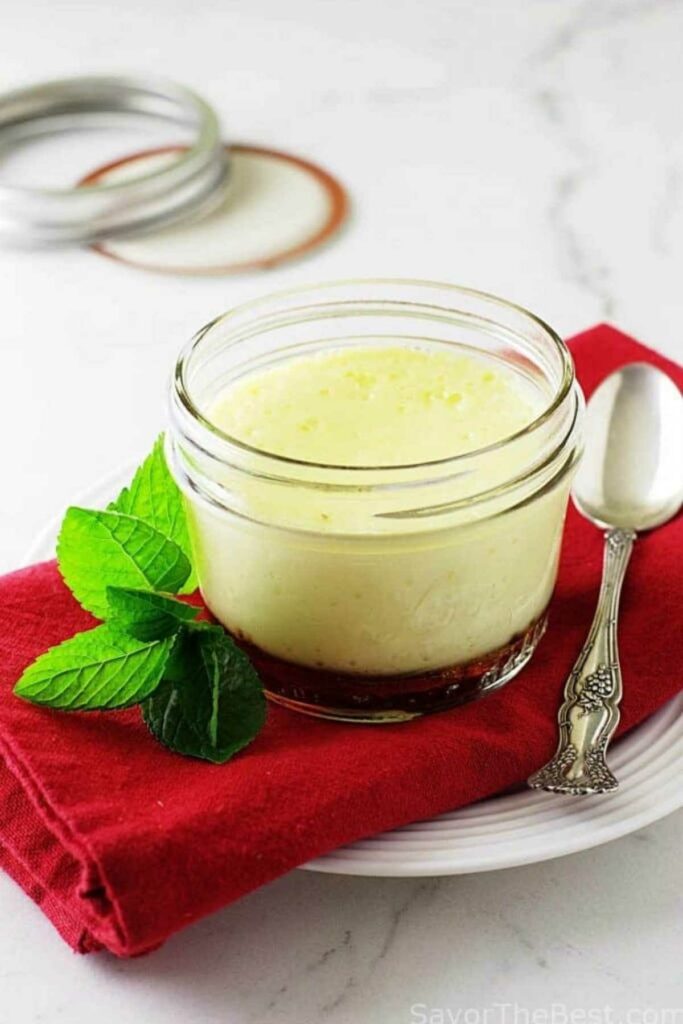 Creamy dessert in a glass jar with mint on plate, red napkin, spoon.